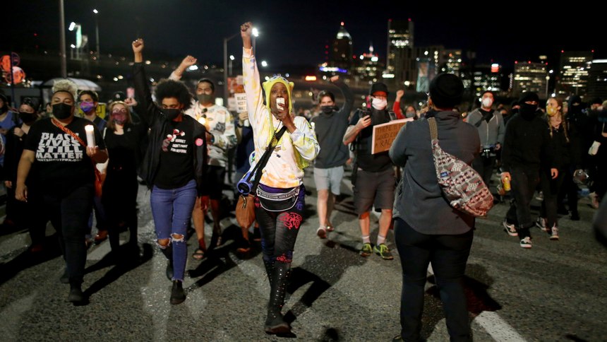 A group marches along the Hawthorne Bridge after meeting at Salmon Street Springs and listening to several Black and Indigenous speakers talk, Friday, April 16, 2021, in Portland, Ore.