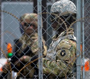 National Guard members are seen through fencing and wire near the Minneapolis Police 3rd Precinct in Minneapolis on Monday, April 19, 2021, after the murder trial against former police Officer Derek Chauvin advanced to jury deliberations.