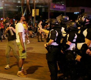 In this May 29, 2020 file photo, police officers stand together, as people protest in downtown Columbus, Ohio, over the death of George Floyd in police custody Monday in Minneapolis.