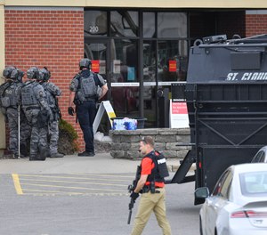 Officers stand near an entrance to the Wells Fargo branch Thursday May 6, 2021, in south St. Cloud, Minn. following a reported hostage situation. Police in Minnesota were on the scene Thursday of a reported bank robbery with hostages.