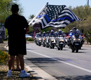 People line the streets as the body of Chandler Police Officer Christopher Farrar, killed in the line of duty is escorted during a large multi-jurisdiction police procession Friday, May 7, 2021, in Chandler, Ariz.
