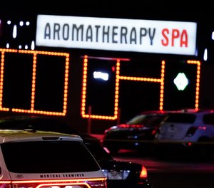 In this Tuesday, March 16, 2021, file photo, officials stand in front of a massage parlor after a shooting, in Atlanta.