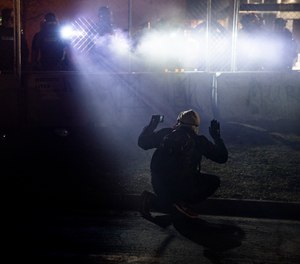 In this April 14, 2021, file photo, police shine lights on a demonstrator with raised hands during a protest outside the Brooklyn Center Police Department on in Brooklyn Center, Minn., over the fatal shooting of Daunte Wright.