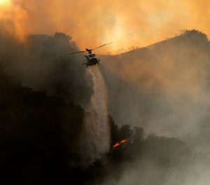 A firefighting helicopter drops water onto a brush fire in the Pacific Palisades area of Los Angeles on Saturday, May 15. The Palisades Fire has burned more than 1,300 acres and forced the evacuation of about 1,000 Los Angeles residents.