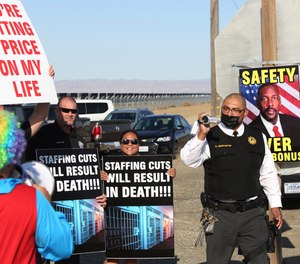 Special investigative services Lt. Armando Cervantes, right, films protesters at the Federal Correctional Institution at Mendota during a demonstration over staffing shortages, near the prison entrance in Mendota, Calif., Monday, May 17, 2021.