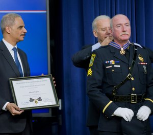 In this Feb. 11, 2015, file photo, Attorney General Eric Holder and Vice President Joe Biden award the Medal of Valor to Sgt. Jeffrey Pugliese from the Watertown, Mass., Police Department, during a ceremony in Washington.