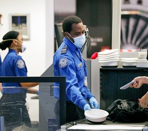 In this May 18, 2020, file photo, Transportation Security Administration officers work security screening area at Seattle-Tacoma International Airport in SeaTac, Wash.