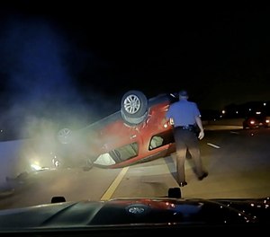 This screen shot taken from dash cam video owned by the Arkansas State Police shows trooper Rodney Dunn walking toward a flipped car in Pulaski County, Ark., on July 9, 2020.