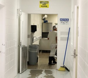 In this photo taken Sept. 10, 2019, a detainee works in a kitchen area at the GEO Group’s immigration jail in Tacoma, Wash., during a media tour.