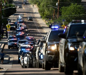 Dozens of police vehicles line up to take part in a procession held in the aftermath of a shooting in Olde Town Arvada that took the life of a police officer on Monday, June 21, 2021 in Arvada, Colo.