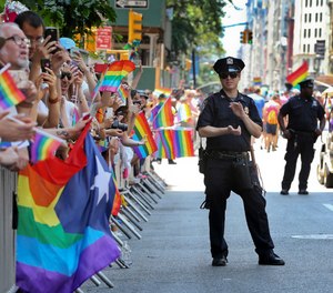 A police officer applauds as parade-goers shout and wave flags during the New York City Pride Parade, Sunday, June 26, 2016 in New York.