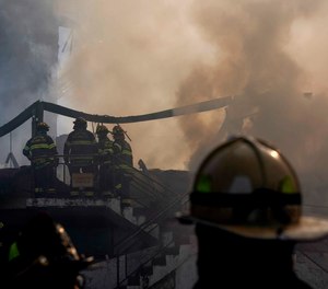 Firefighters stand at the smoldering aftermath of a fire that burned down the Evergreen Court Home for Adults, in Spring Valley, N.Y. Six people are facing charges in connection with the fire that killed a firefighter and a facility resident.