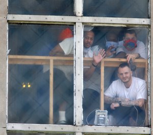 In this April 28, 2020, photo, inmates at the Westville Correctional Facility in Westville, Ind., watch protesters from a window. The protesters wanted better safety measures after an outbreak of COVID-19 cases at the prison.