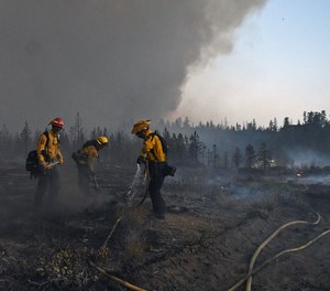 In this Monday, June 28, 2021, photo firefighters with the California Department of Forestry and Fire Protection work to extinguish hot spots after the Lava Fire burned through an area alongside U.S. Highway 97 northeast of Weed, Calif. A wildfire that has put thousands of people under evacuation orders in Northern California grew substantially but firefighters had some success against the flames, authorities said Wednesday, June 30. Burning in the shadow of the towering Mount Shasta volcano, the Lava Fire was ignited by lightning last week.