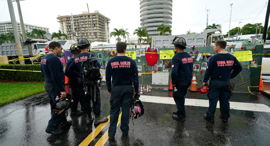 Members of the Coral Gables Fire Department pay their respects at a makeshift memorial to the people killed after the partial collapse of the Champlain Towers South condo building.