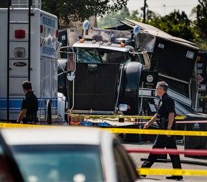 Police officers walk past the remains of an armored Los Angeles Police Department tractor-trailer July 1, 2021, after illegal fireworks seized at a home exploded in South Los Angeles.