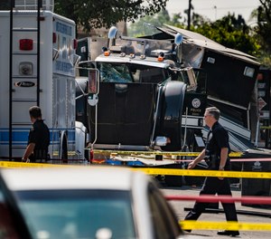 Police officers walk past the remains of an armored Los Angeles Police Department tractor-trailer July 1, 2021, after illegal fireworks seized at a home exploded in South Los Angeles.