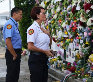 From left, Miami-Dade Fire Rescue personnel Fai Yeung and Chief Melanie C. Adams visit the makeshift memorial setup near the partially collapsed 12-story Champlain Towers South Condo in Surfside, Fla., Thursday, July 1, 2021. Search is paused because of structural concerns officials say. The apartment building partially collapsed on Thursday, June 24