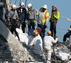 Search and rescue personnel remove remains on a stretcher as they work atop the rubble at the Champlain Towers South condo building where scores of people remain missing more than a week after it partially collapsed, Friday, July 2, 2021, in Surfside, Fla. Rescue efforts resumed Thursday evening after being halted for most of the day over concerns about the stability of the remaining structure