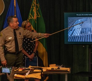 Los Angeles County Sheriff Alex Villanueva, and Los Angeles County Supervisor Kathryn Barger stand in front of confiscated firearms, as he points to a picture of some 500 illegal pot operations at a news conference downtown Los Angeles Wednesday, July 7, 2021.
