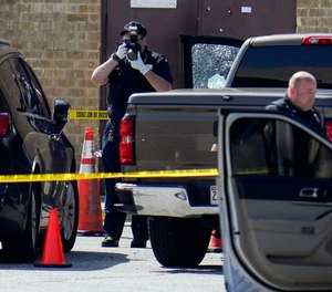 Shattered glass is seen on a pickup's driver side door as investigators document the scene in a mall parking area where two Baltimore city police officers were shot and a suspect was killed as a U.S. Marshals’ task force served a warrant, Tuesday, July 13, 2021, in Baltimore, Md.