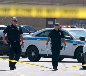 Baltimore Police officers inspects an area where two officers on a U.S. Marshals' task force were shot onTuesday, July 13, 2021.