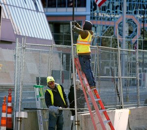 In this Wednesday, Feb. 23, 2021 file photo, workers install barbed wire on fencing outside the Hennepin County Government Center in Minneapolis, as part of security preparation for the trial of Derek Chauvin.