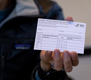 In this Jan. 10, 2021 file photo, a nurse practitioner holds a COVID-19 vaccine card at a clinic in Brooklyn, New York.
