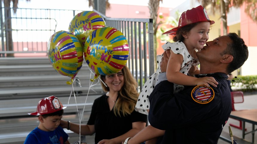 Capt. Eric Hernandez lifts up his daughter Isabella, 3, as his wife Yaimara and son Eric, 4, look on, as members of Miami-Dade Fire Rescue's urban search and rescue team are reunited with their families after weeks of working on the rubble pile at the collapsed Champlain Towers South condominium, on Friday, July 23, 2021, in Doral, Fla.