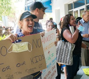 Joann Marcus of Fort Lauderdale, left, cheers as she listens to the Broward School Board's emergency meeting, Wednesday, July 28, 2021, in Fort Lauderdale, Fla.