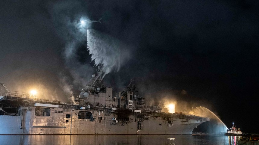 A helicopter from Helicopter Sea Combat Squadron (HSC) 3 combats a fire aboard the amphibious assault ship USS Bonhomme Richard (LHD 6) at Naval Base San Diego.