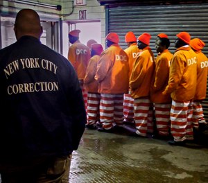 In this March 16, 2011 file photo, a corrections official watches inmates file out of a prison bakery after working the morning shift at the Rikers Island jail in New York.