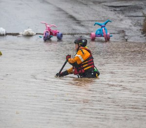 A member of a rescue team walks through a flooded street on Wednesday, Sept. 1, 2021, in Bridgeville, Pa. Pennsylvanians braced for downpours and high winds from the remnants of Hurricane Ida, with forecasters warning that creeks, streams and rivers would be inundated across the state's southern tier.