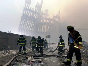 Firefighters work beneath the destroyed mullions, the vertical struts, of the World Trade Center in New York on Tuesday, Sept. 11, 2001.