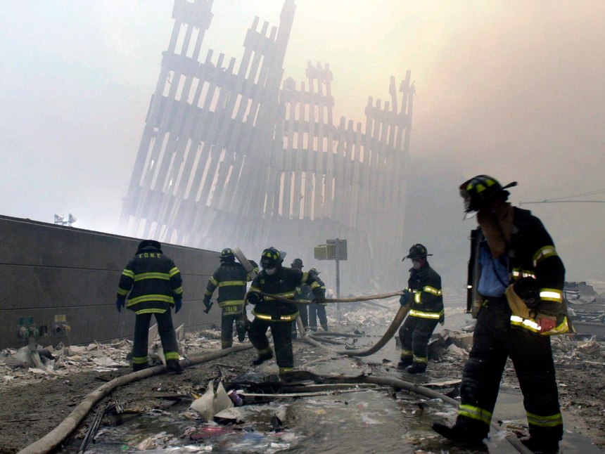 With the skeleton of the World Trade Center twin towers in the background, FDNY firefighters work amid debris on Cortlandt St. after the terrorist attacks of Tuesday, Sept. 11, 2001.