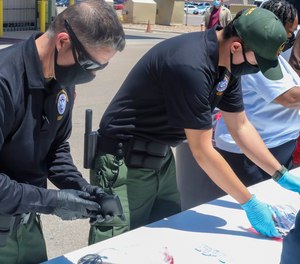 This May 4, 2021, photo provided by The U.S. Border Patrol shows U.S. Border Patrol Processing Coordinators help process and log personal items from migrants entering the Central Processing Center in El Paso, Texas.