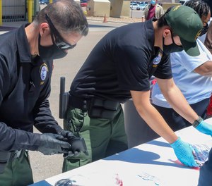 This May 4, 2021, photo provided by The U.S. Border Patrol shows U.S. Border Patrol Processing Coordinators help process and log personal items from migrants entering the Central Processing Center in El Paso, Texas.