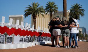 In this Oct. 1, 2019, file photo, people pray at a makeshift memorial for shooting victims in Las Vegas on the anniversary of the mass shooting.