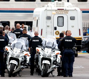Tucson Police officers and other law enforcement officers stand at attention as the body of a Drug Enforcement Administration special agent is removed from an Amtrak train and loaded into a van from the Pima County Medical Examiner following a shooting Monday, Oct. 4, 2021, in Tucson, Ariz.