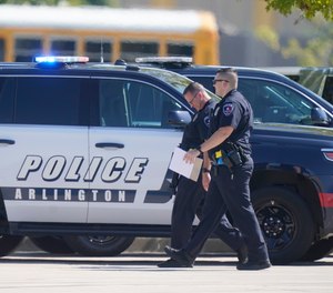 Law enforcement officers walk in the parking lot of Timberview High School after a shooting inside the school located in south Arlington, Texas, Wednesday, Oct. 6, 2021.