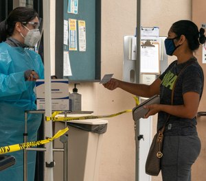 A patient shows her COVID-19 vaccination card to a healthcare worker in Los Angeles.