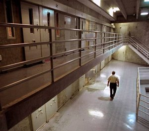 A correctional officer walks through a housing unit during a lockdown at California State Prison, Sacramento, in Folsom, Calif.