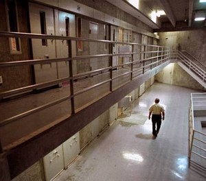 A correctional officer walks through a housing unit during a lockdown at California State Prison, Sacramento, in Folsom, Calif.