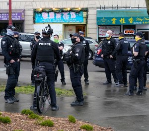 Seattle Police officers confer after taking part in a public roll call at Hing Hay Park in Seattle's Chinatown-International District Thursday, March 18, 2021.