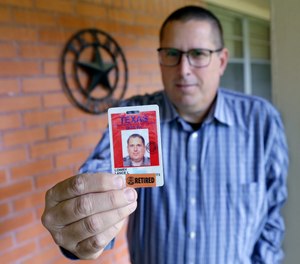 Lance Lowry, a recently retired corrections officer with the Texas State Penitentiary, holds his ID badge on the front porch of his home, Oct. 27, 2021, in Huntsville, Texas.