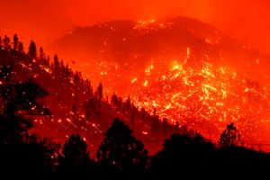 In this Aug. 17, 2021, photo, embers light up hillsides as the Dixie Fire burns near Milford in Lassen County, Calif.