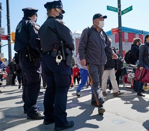 Two New York City Police officers patrol a busy intersection on Main Street in the Flushing neighborhood of Queens on Tuesday, March 30, 2021