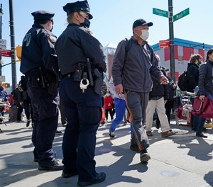 Two New York City Police officers patrol a busy intersection on Main Street in the Flushing neighborhood of Queens on Tuesday, March 30, 2021