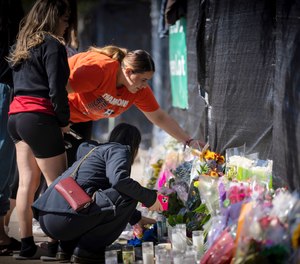 Stacey Sarmiento places flowers at a memorial in Houston on Sunday, Nov. 7, 2021 in memory of her friend, Rudy Pena, who died in a crush of people at the Astroworld music festival on Friday.