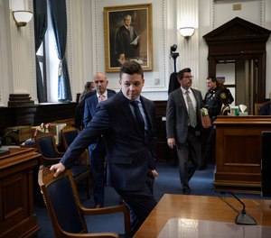 Kyle Rittenhouse, center, pulls out his chair for a meeting Judge Bruce Schroeder called during his trial at the Kenosha County Courthouse in Kenosha, Wis., on Thursday, Nov. 18, 2021.